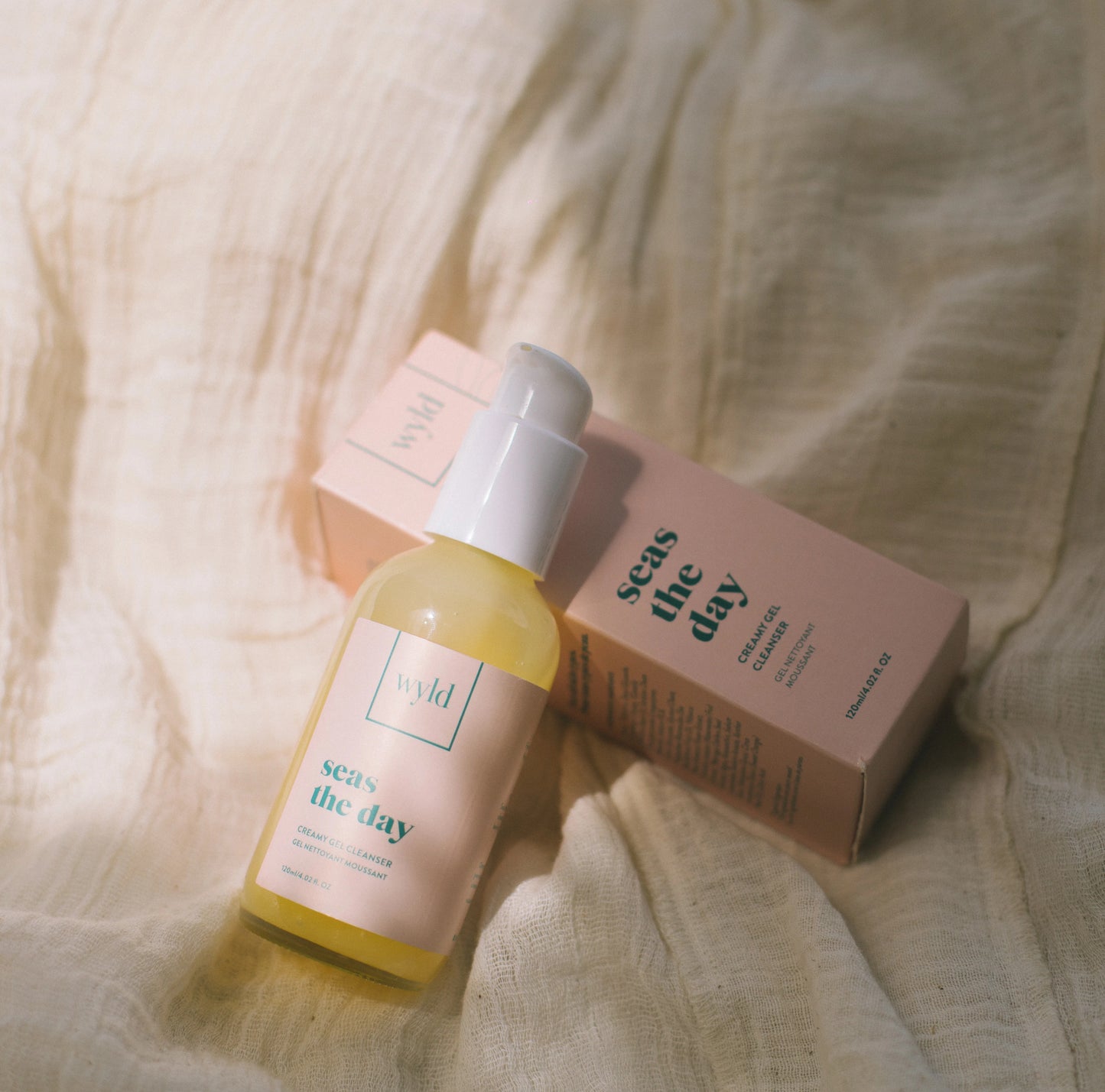 An image of a cleanser laying on the packaging, on top of a fabric.
