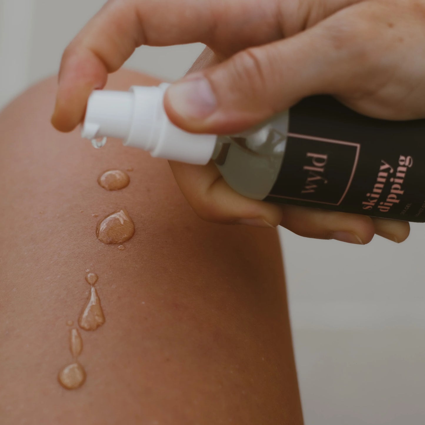 A hand applying Wyld Skinny Dipping lubricant on a leg.