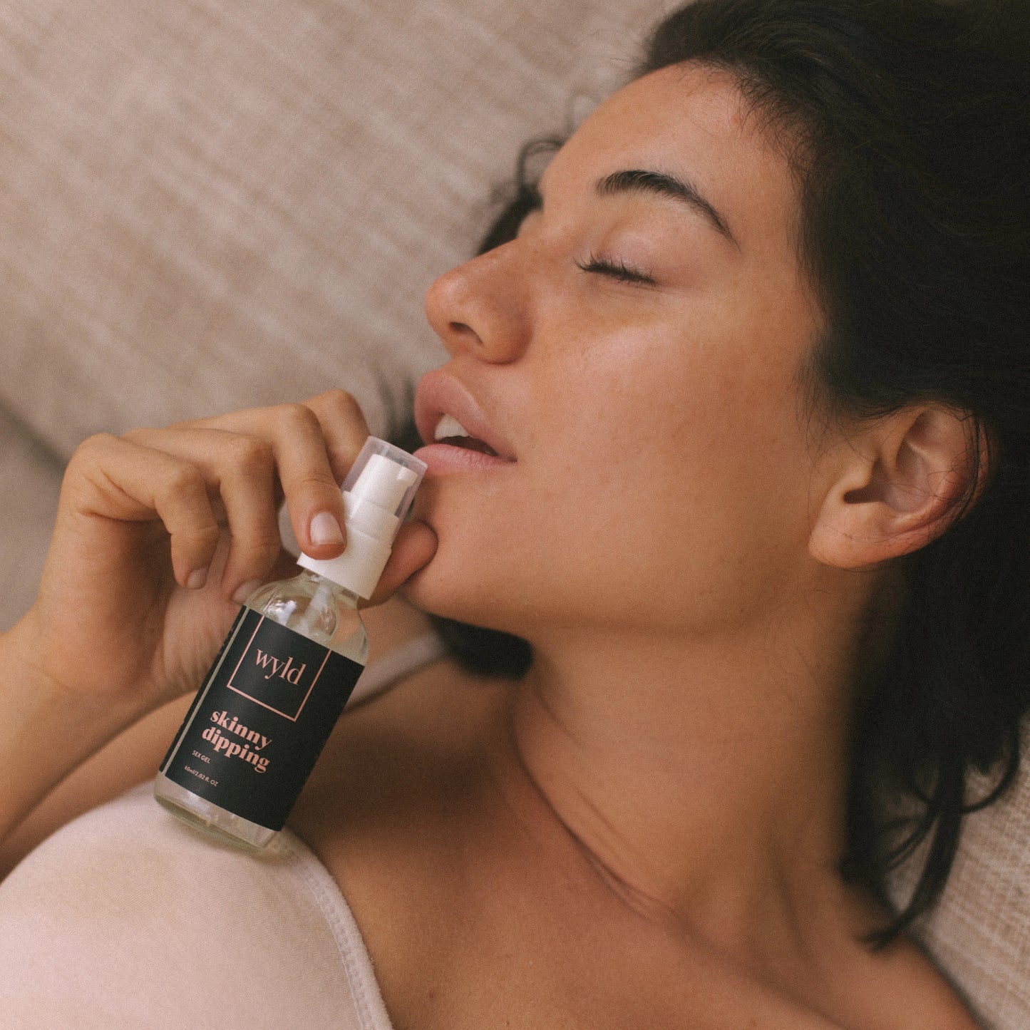 A woman holding a bottle of Wyld Skinny Dipping lubricant.
